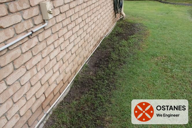 Exposed slab edge and damp ground along the side of a brick veneer home