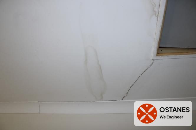 Water-stained and cracked ceiling lining beside a skylight opening